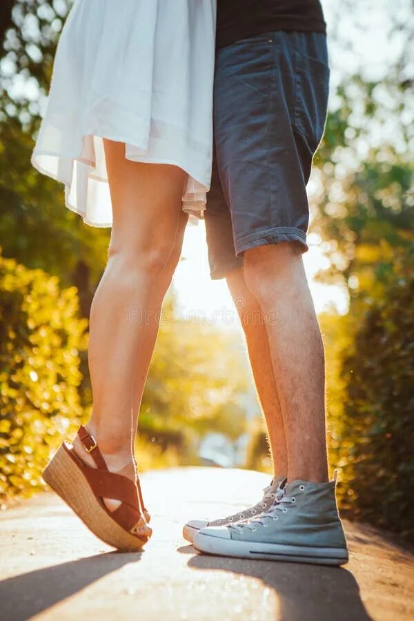 Девушка обнимает ноги. Ноги девушки на парне. Поцелуй под ног. Целование ног на улице. Обнимашки на носочках.