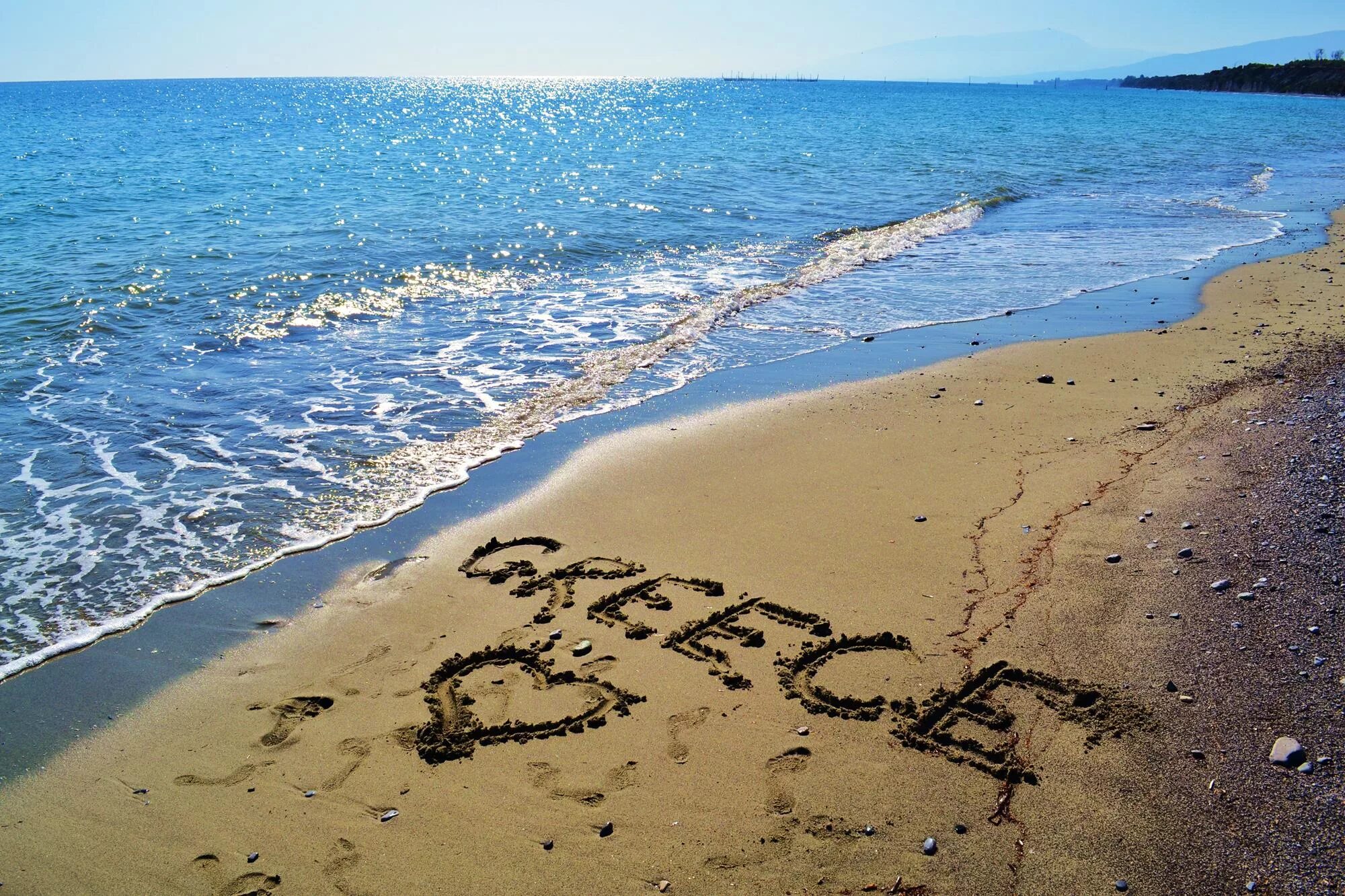 Добро на греческом. Надпись на песке. Надпись на песке на море. Греция море любовь. Отдых на море.