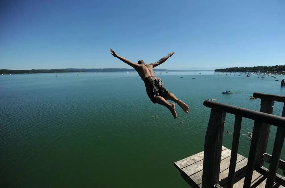 Парень прыгает в воду. Прыжок в озеро. Девушка прыгает в воду. Пирс для ныряния.