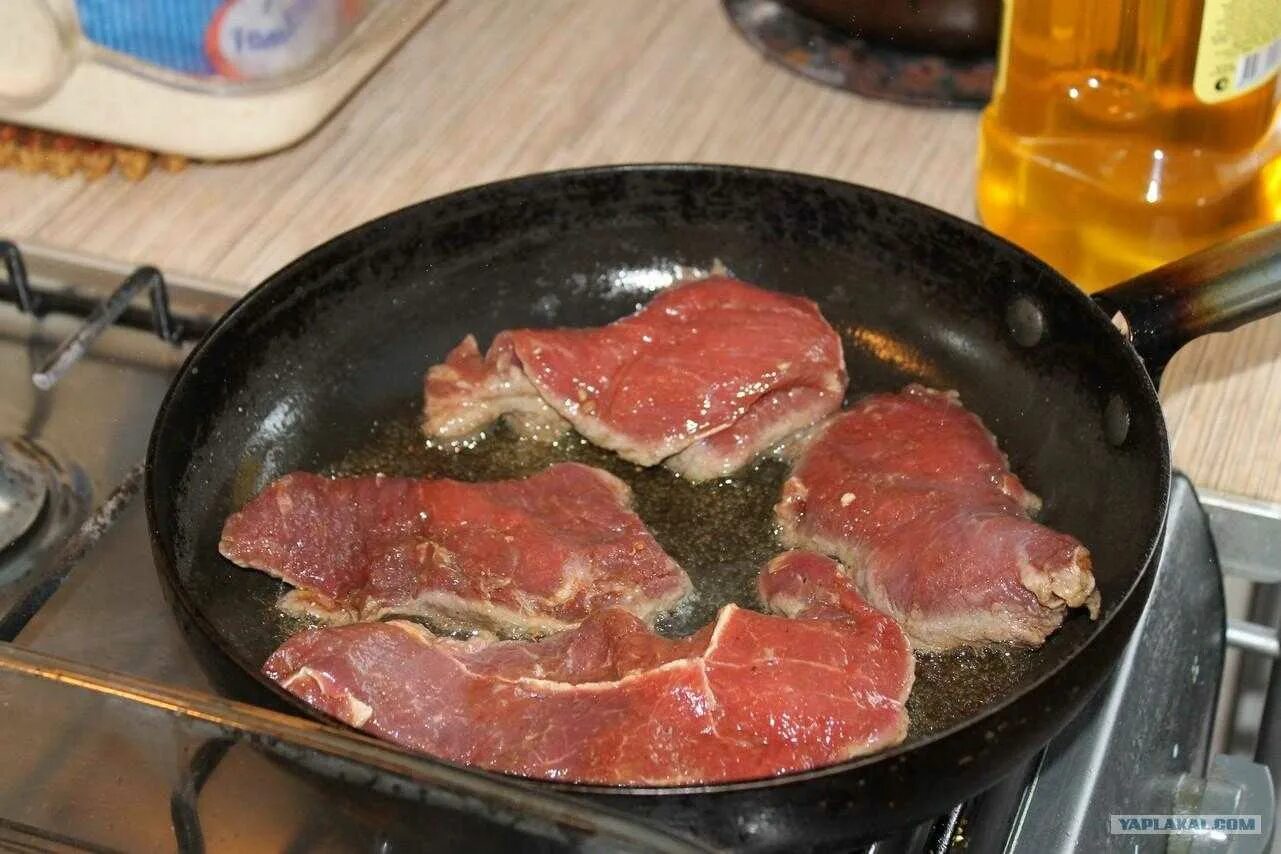 Есть сырое плохо проваренное прожаренное мясо. Мясо на сковороде. Говядина на сковороде. Кусок жареного мяса. Жареная говядина на сковороде.