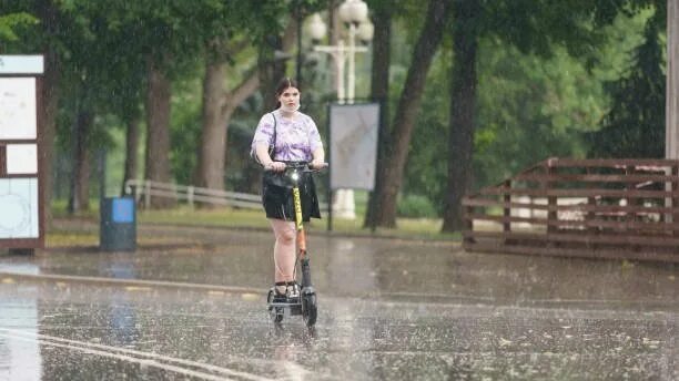 Можно ли электросамокат в дождь. На самокате под дождем. На самокате в дождь. На скутере в дождь. Самокат зонт дождь.