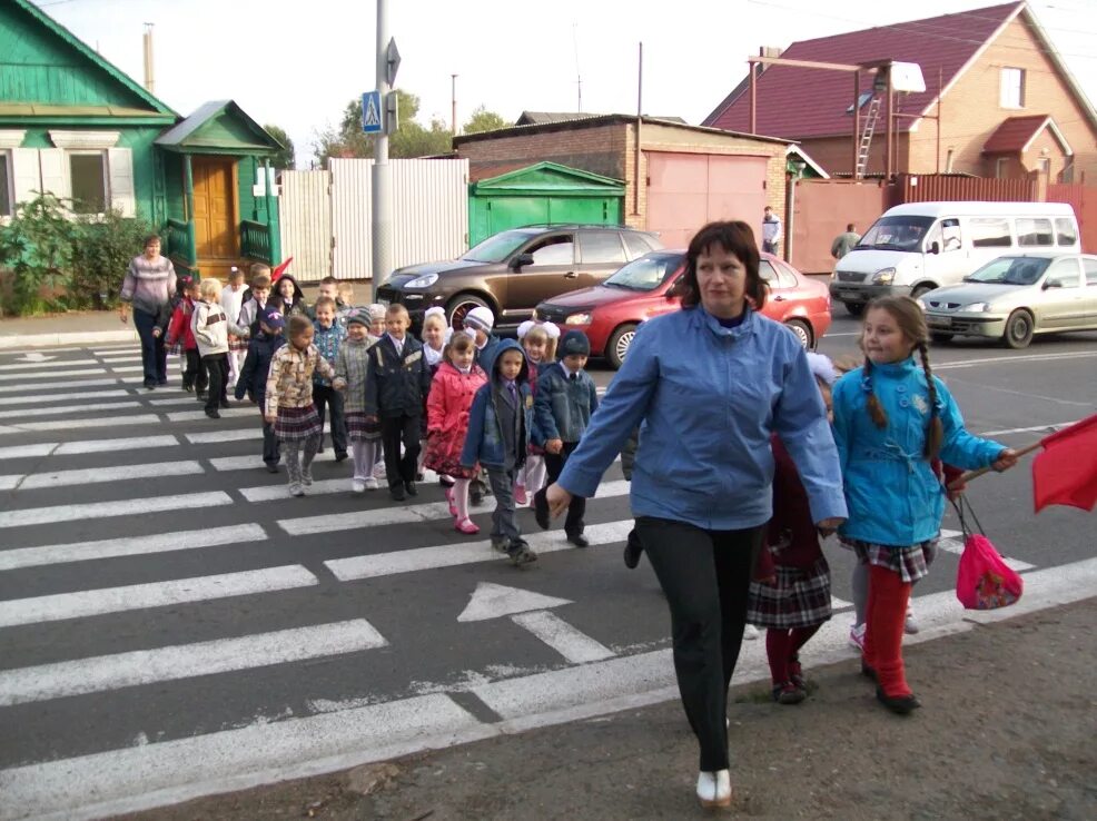 Перевести дол. Учитель ведет детей через дорогу. Группа детей на дороге. Школьники переходят дорогу. Организованные пешие колонны.