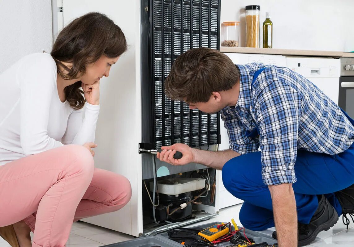 Починка холодильника. Холодильник вышел из строя. Мужчины занимающиеся ремонтом холодильников. Мастер холодильников. Мастер чинит холодильник.