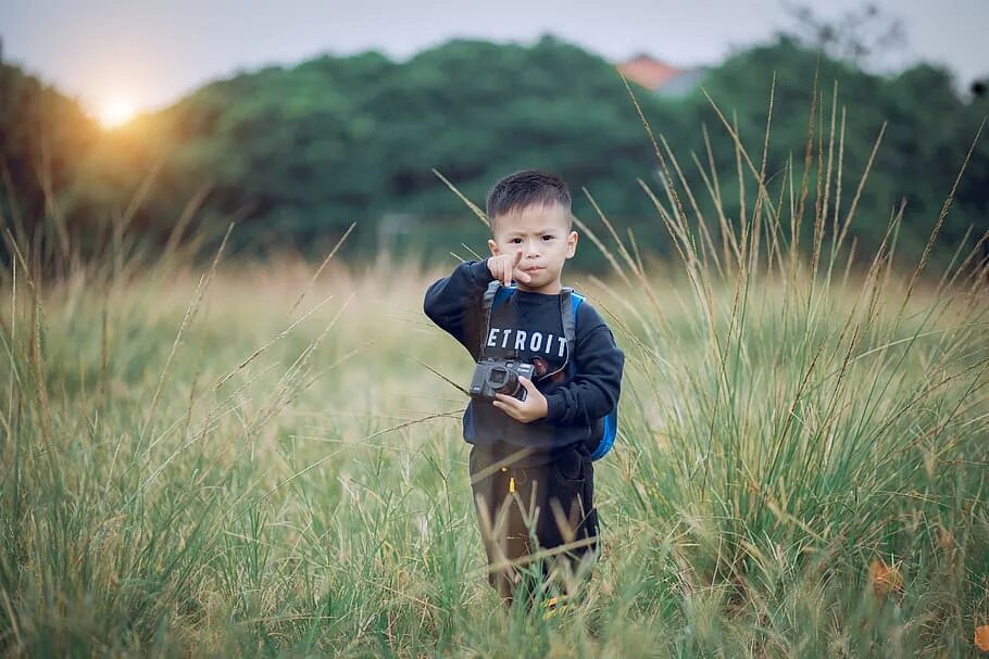 Мальчик фотографирует. Дети издалека. Мальчик в зеленом поле. Свободный ребенок.