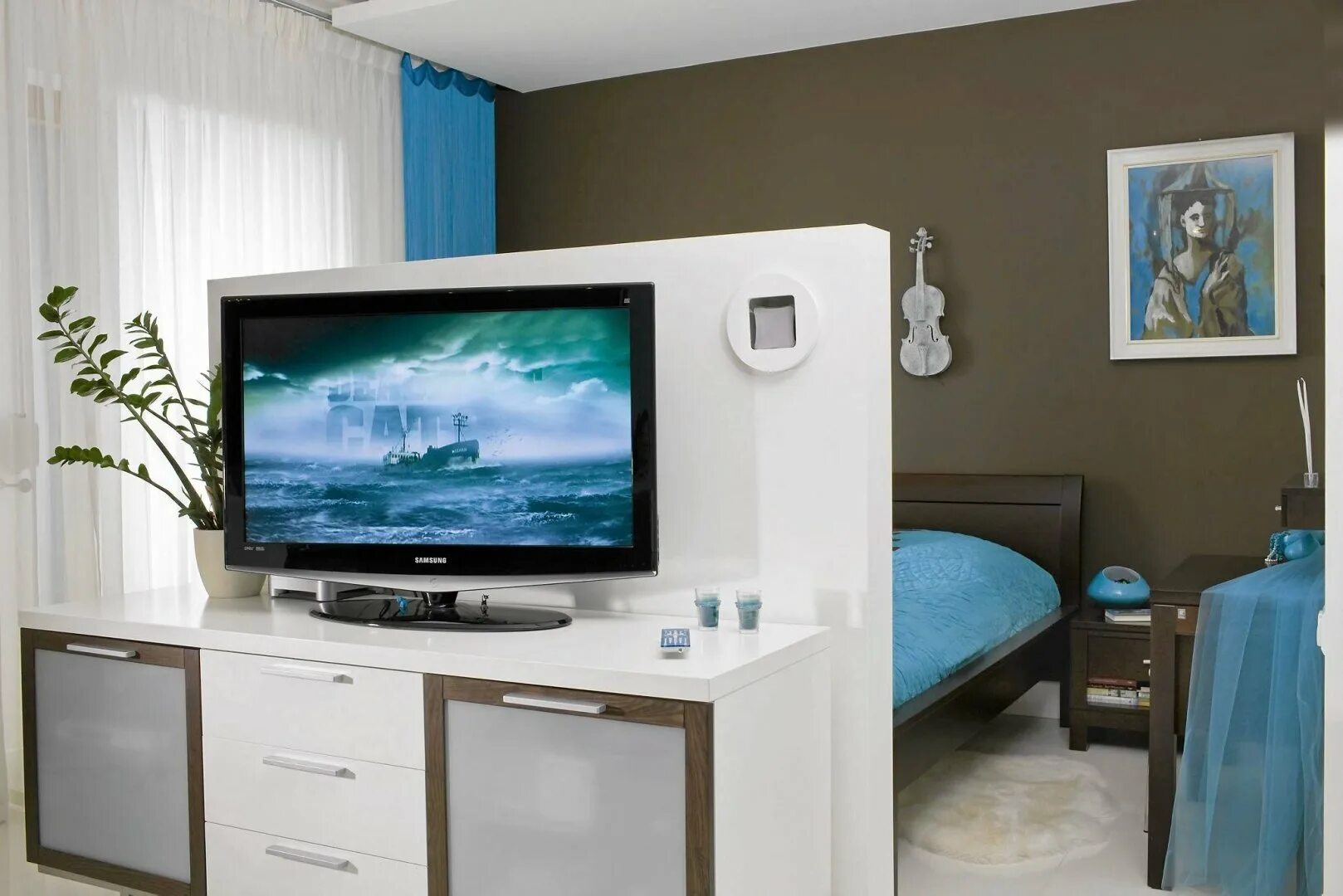 Телевизор в спальне. Телевизор в центре комнаты. Спальня с перегородкой для телевизора. Телевизор на тумбе посреди комнаты.