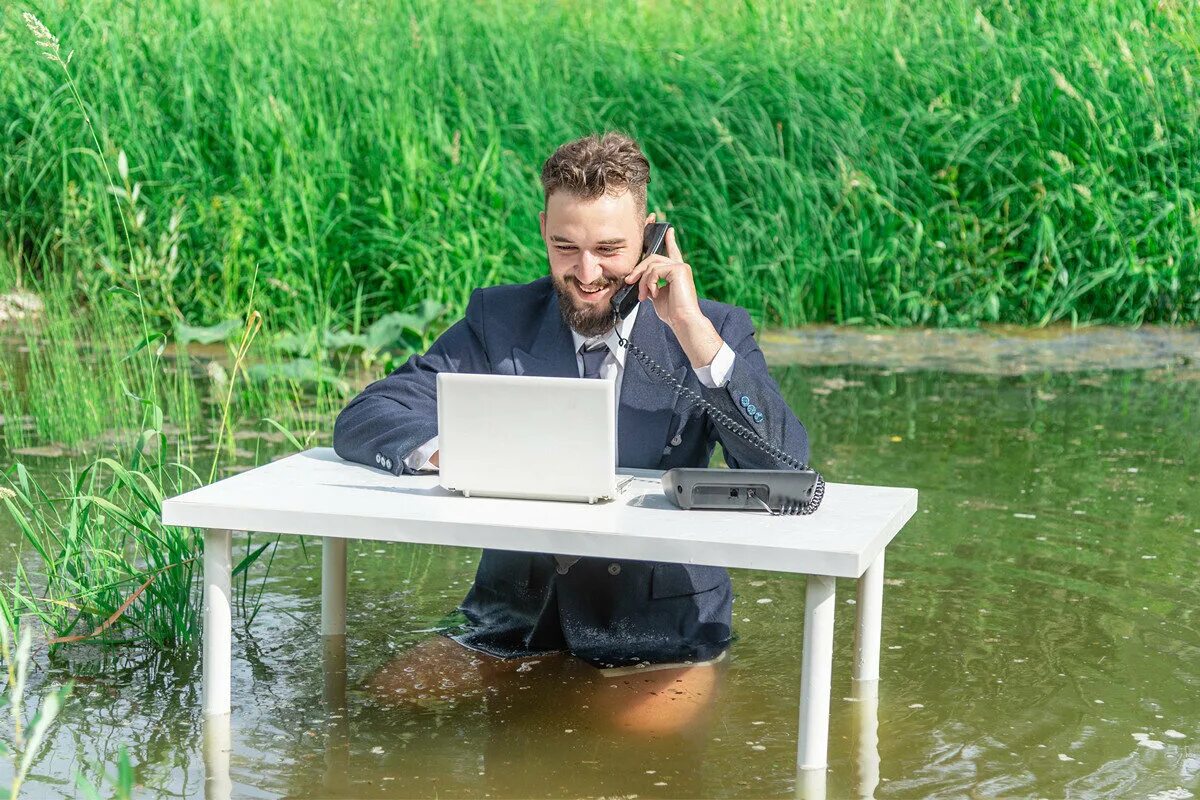 Человек на удаленке. Человек в болоте за столом. Парень сидит в болоте за столом. Офисный работник в болоте. Working dick