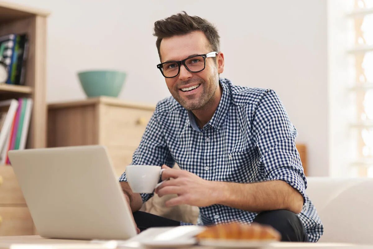Аналитик на фрилансе. Человек за компьютером. Молодой человек с ноутбуком. Мужчина с ноутбуком. Мужчина улыбается.