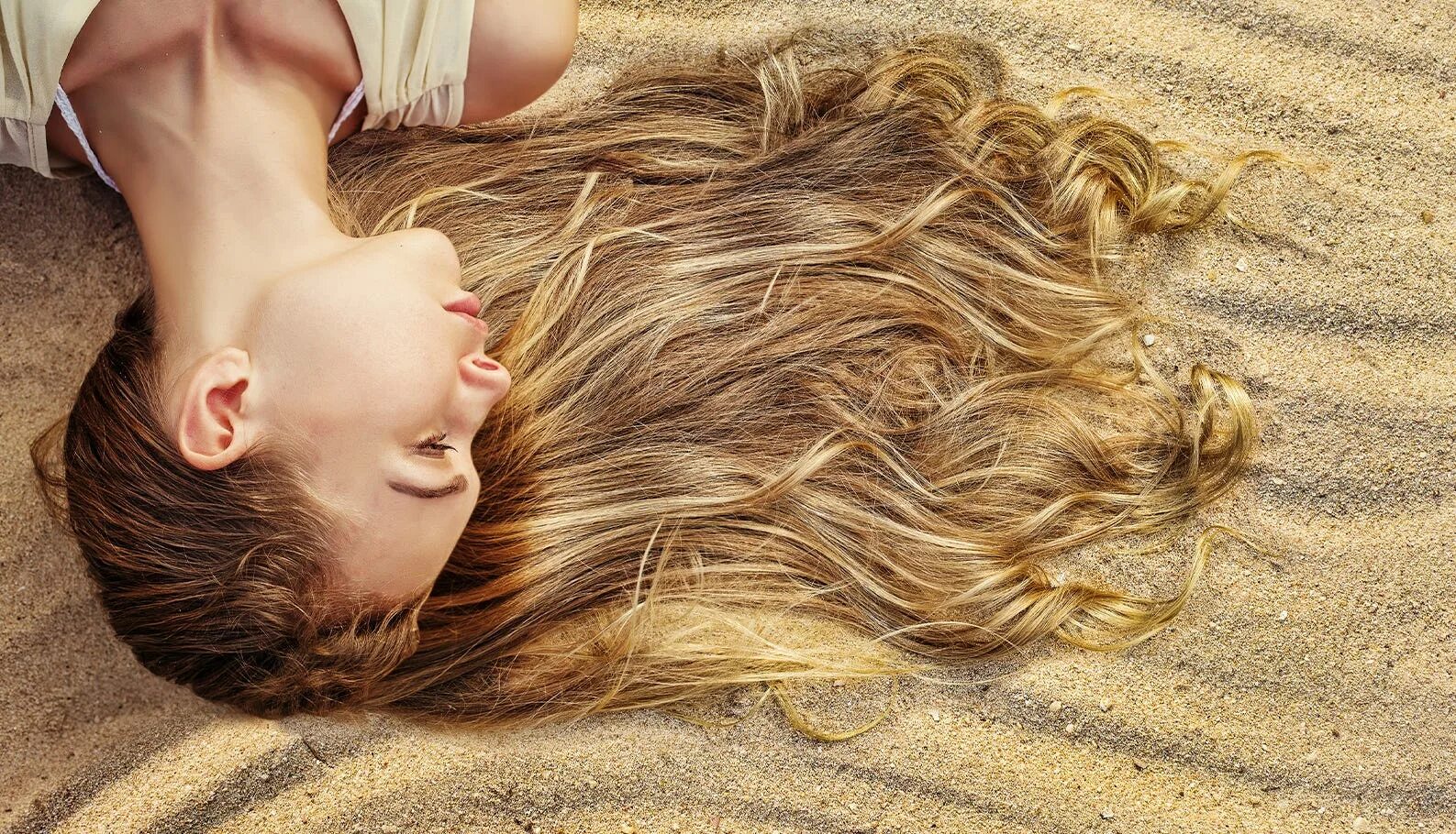 Красивые волосы. Волосы летом. Красивые волосы летом. Девочка лежит на песке.