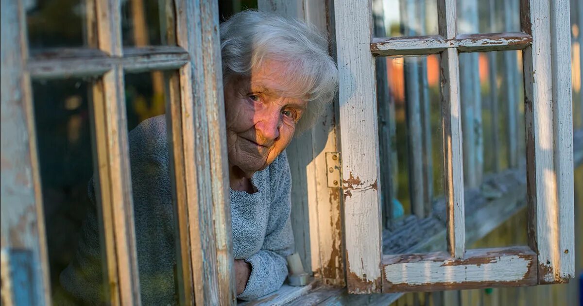 Жилье старика и старухи. Бабуля у окна. Бабушка в окошке. Бабушка у окна в деревне. Пожилая женщина у окна.
