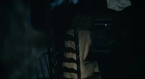 Jill is sitting naked on a dark room. 
