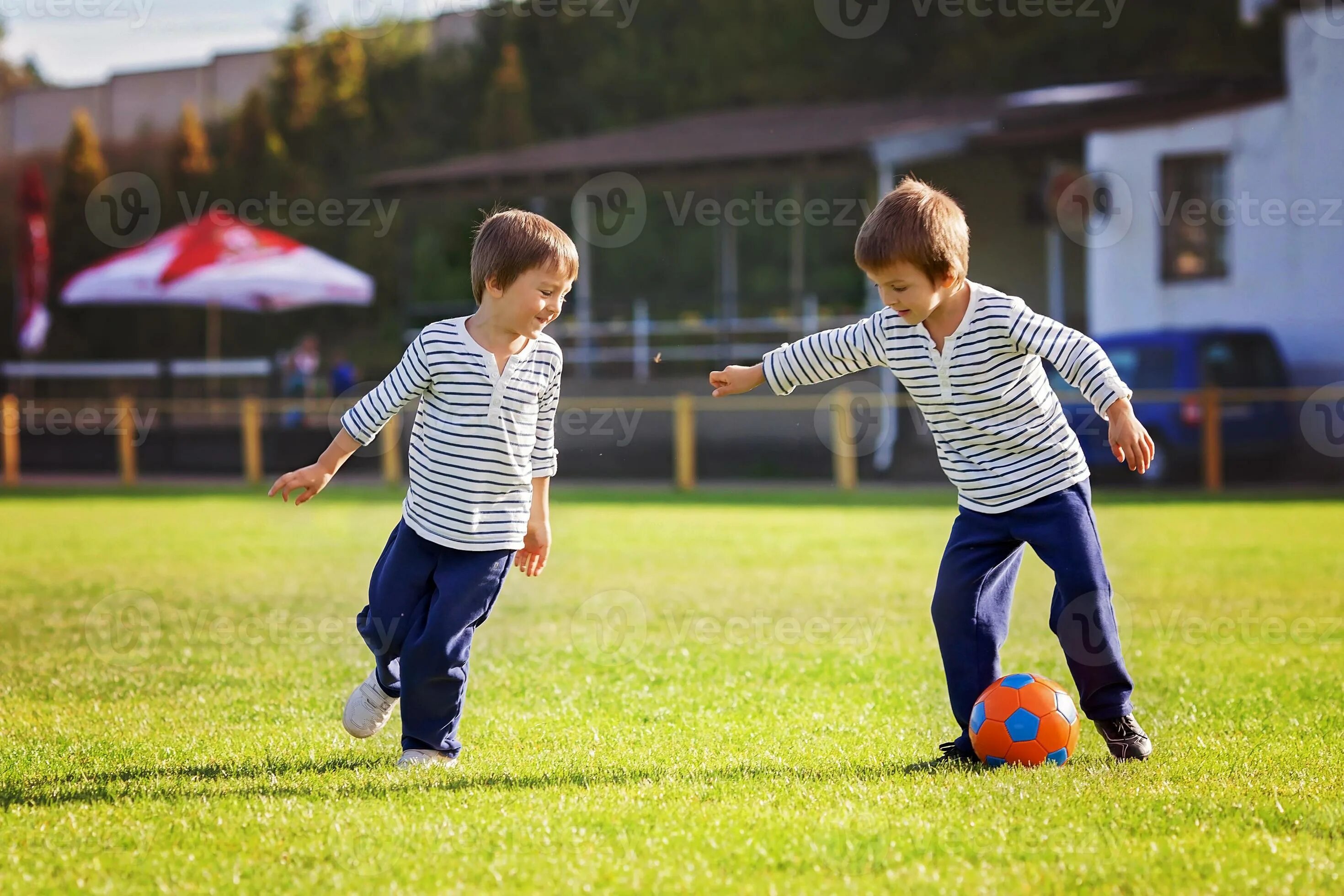 Два мальчика играют в футбол. Мальчики играют в футбол во дворе. Семья играет в футбол. Два друга мальчика играют.