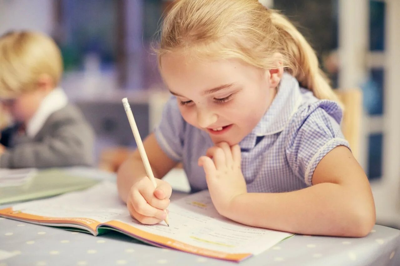 Маленький ребенок делает уроки. Школьник пишет. Дети в школе. Прилежный ученик. Ребенок пишет.