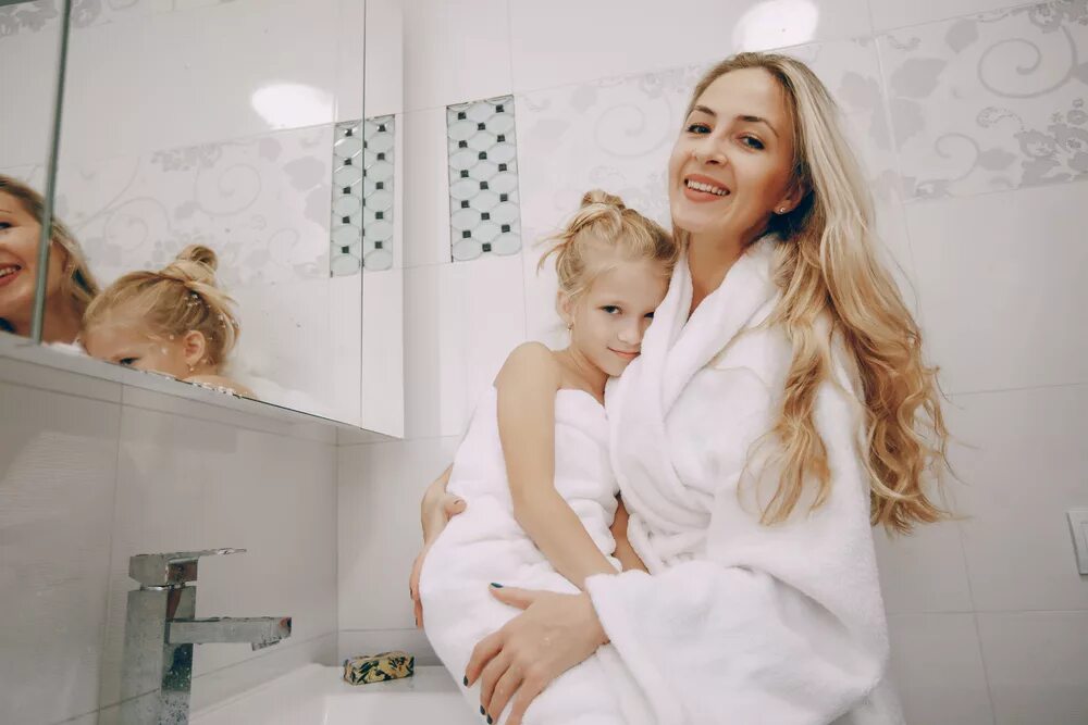 Daughter bath. A young girl Wrapped in a Towel sat on our Bathroom Bench, looking in the Mirror.