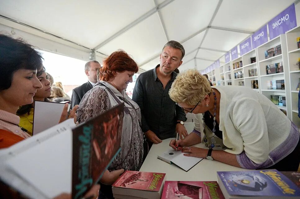 Встреча писателя с читателями. Автограф сессия писательницы. Писательница раздает автографы. Книжный фестиваль в Москве.