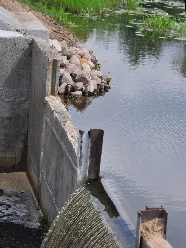 Люди перегородили реку большой плотиной вода. Плотина на ручье. Пруд и запруда. Деревянная плотина на ручье. Плотина на пруду.