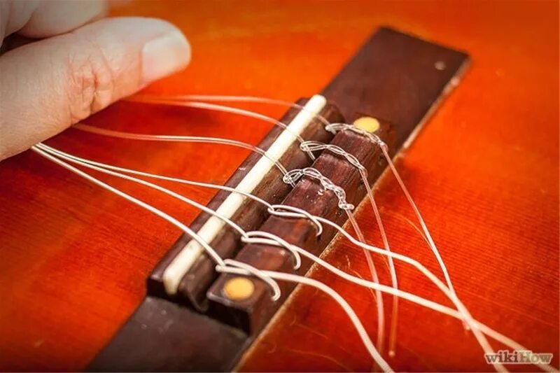 Крепление струн на акустической гитаре. Поменять струны на гитаре. Струна на колках гитаре шесть. Почему изменяя натяжение струны можно изменять. Гитара с нейлоновыми струнами.