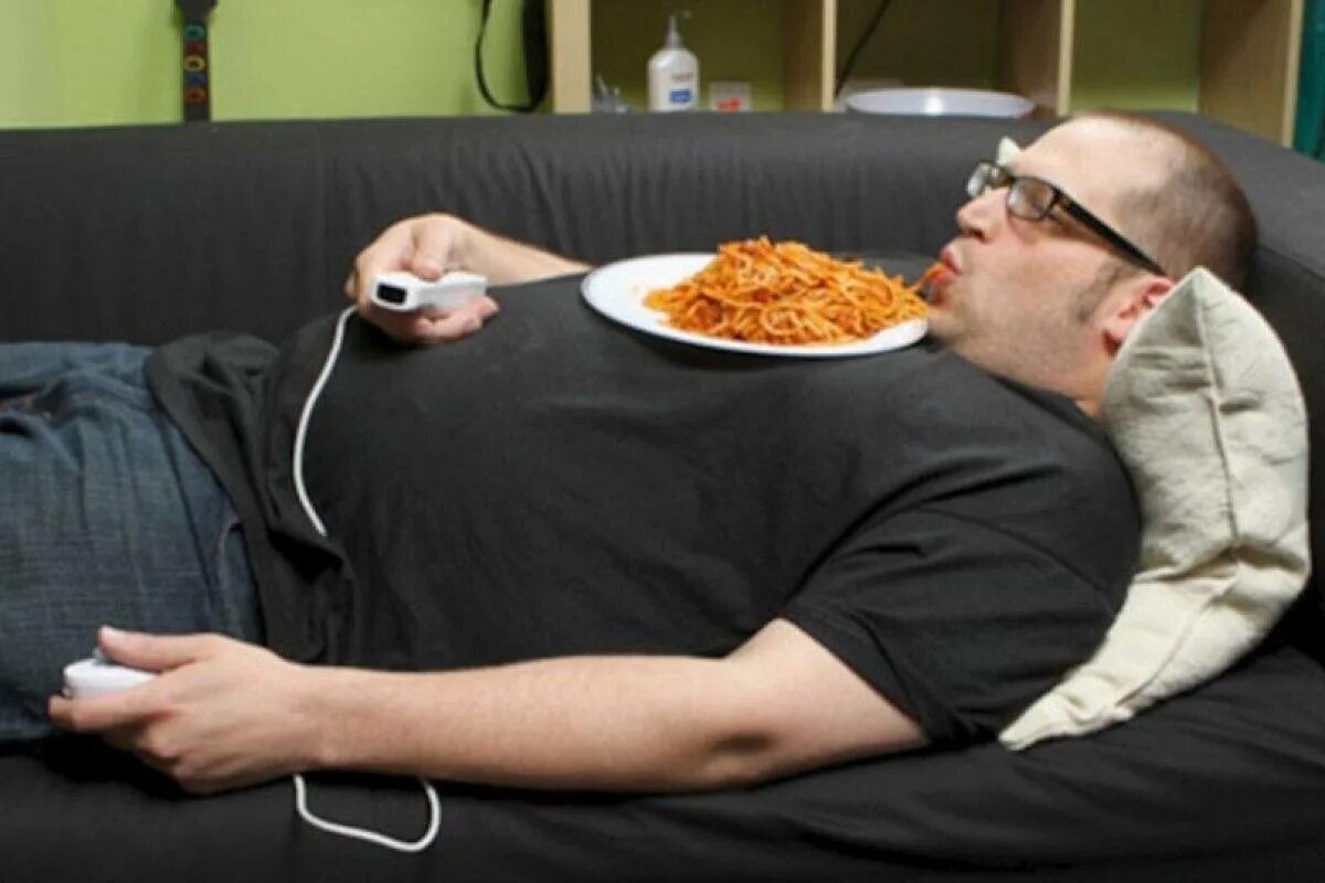 Отдохнуть после обеда. Ленивый человек. Толстый ленивый человек. Толстый человек на диване.