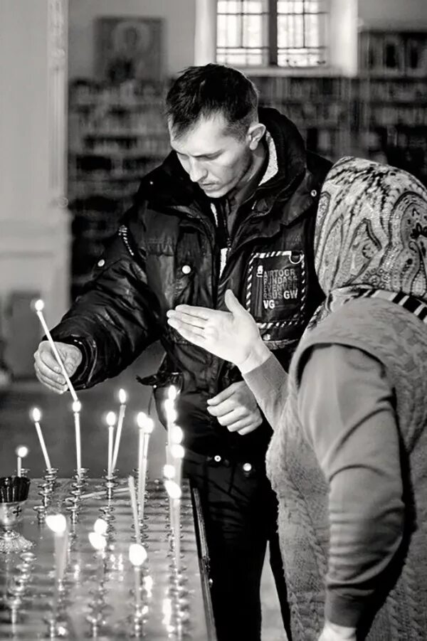 Мужчина ставит свечу. Мужчина в церкви. Парень в церкви. Храм. Мужчина молится в храме.