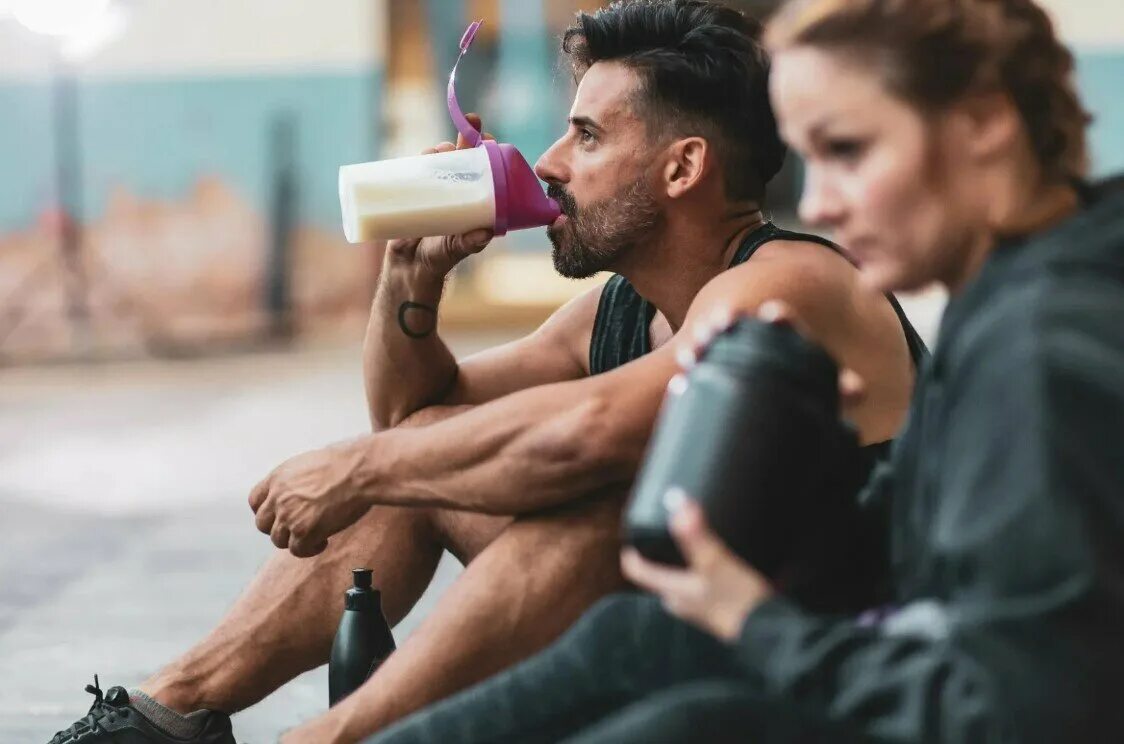 Питание и тренировки. Спортсмен пьет. Спортивное питание для спортсменов. Мужчина пьет протеиновый коктейль.