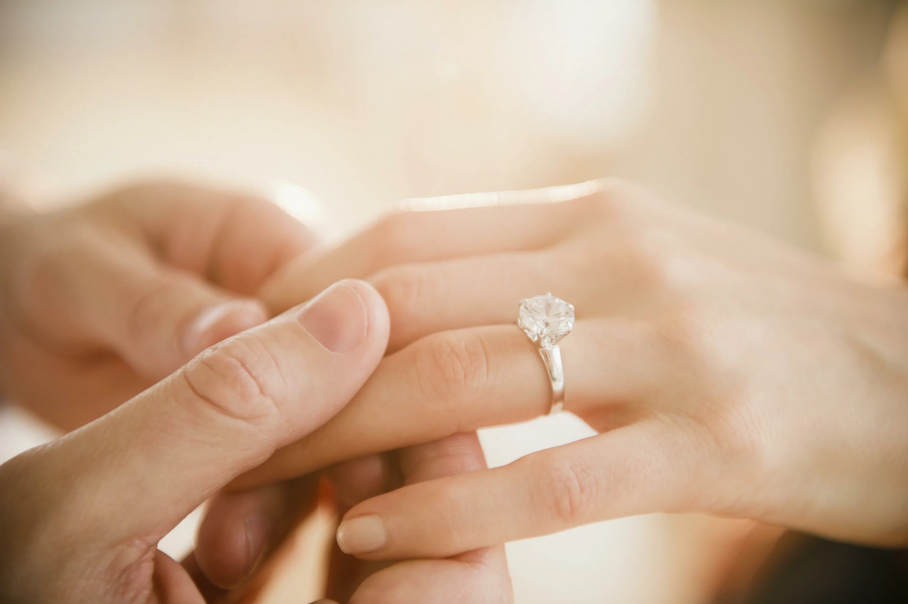 Young Adult Male Hand Putting Engagement Ring on Female Finger Stock Photo - Ima
