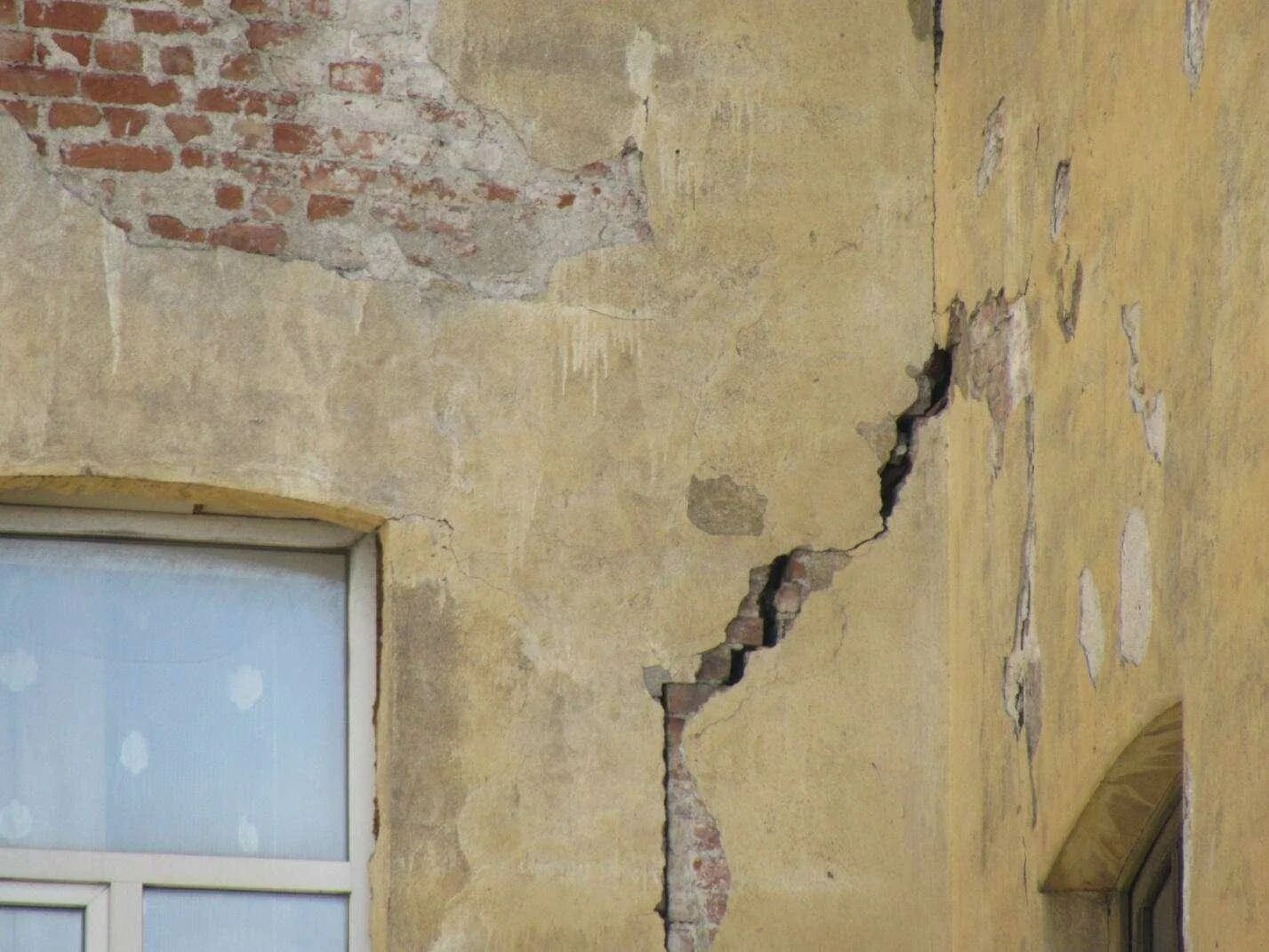 Трещины в стенах дома. Трещина в доме. Трещина в здании. Трещины на фасаде. Трещина в стене дома.
