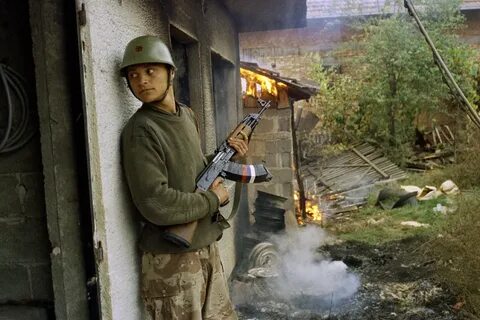 A Serbian soldier takes cover by a burning house in the village of Gorica, ...