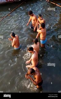 India, Uttar Pradesh, Varanasi, men bathing and praying in the Ganges River...