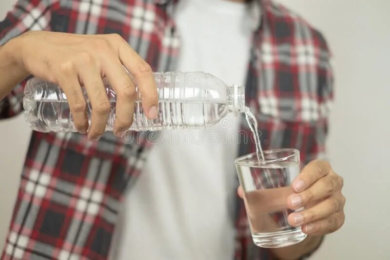 В стеклянную бутылку налили. Налить воду в бутылку. Рука со стаканом в который наливают воду. Мужчина наливает в стакан воды. Рука наливает воду.