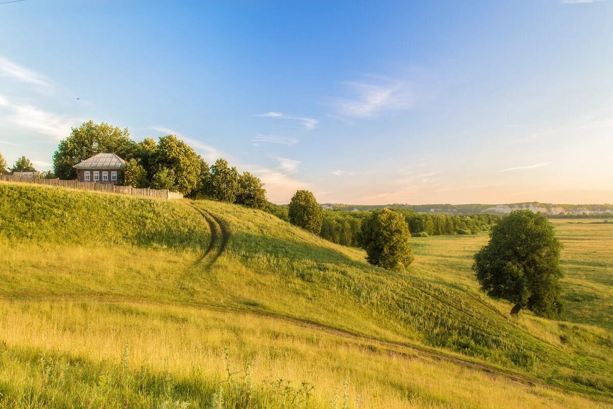 Поле деревня. Обрыв холма. Холмистая равнина рельеф. Горы холмы закат. На пригорке взору открывается.