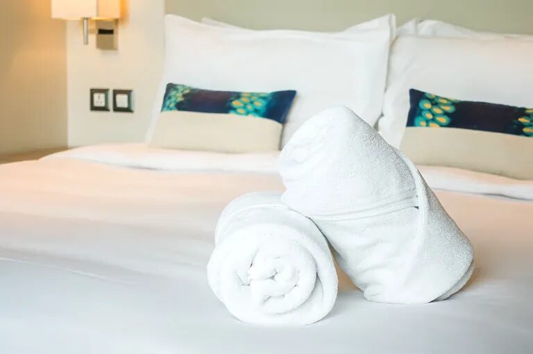 Полотенце на кровати. Полотенца на кровати. Сложенные полотенца на кровати. Полотенца на кровати в гостинице. Белое полотенце на кровати.