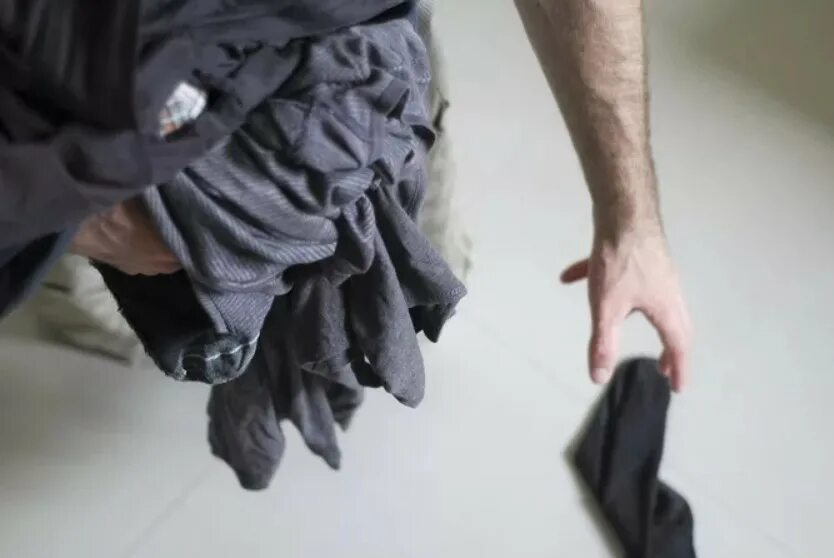 мужчины разбрасывают носки. грязные мужские носки. неряшливый подросток. разбросанные носки по дому. человек под столом.