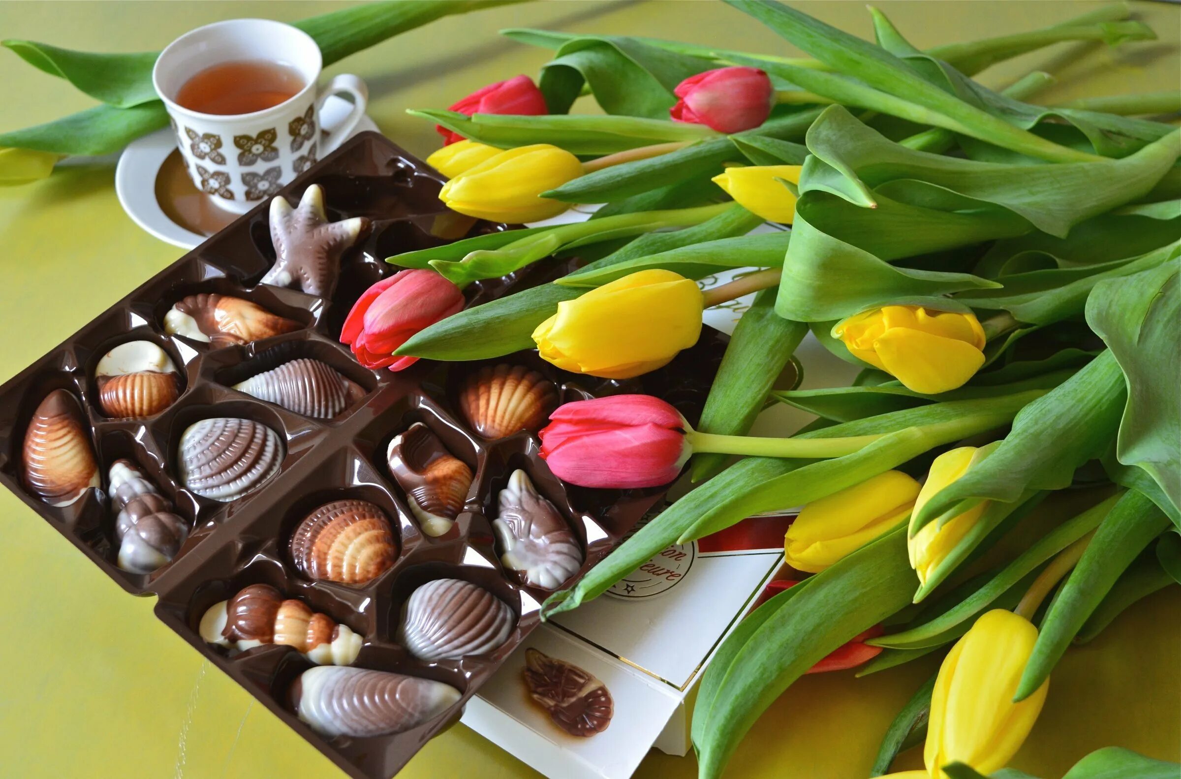 Цветы с конфетами. Шоколадные конфеты и цветы. Конфеты на столе. Цветы и вкусняшки. Шоколад сладкий чай