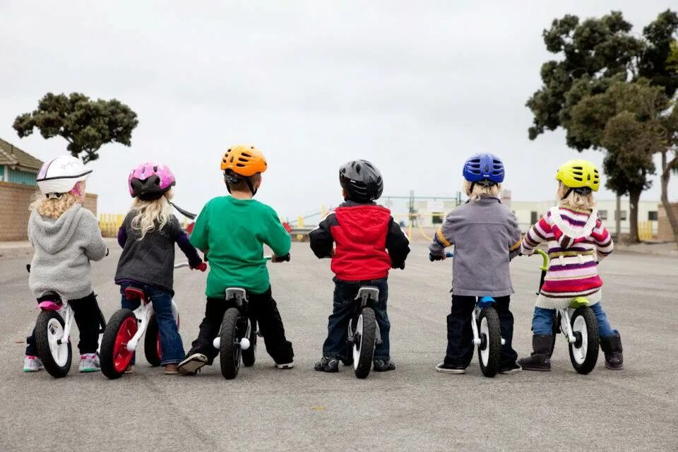 The children are riding bikes. Дети с велосипедом. Ребенок на беговеле. Дети на беговелах гонка. Детские гонки на беговелах.