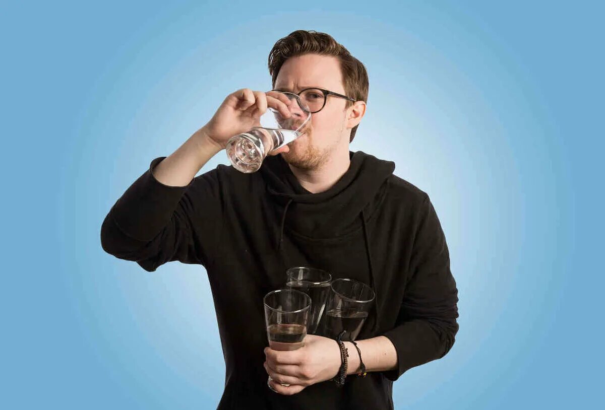 Мужчина пьет воду из стакана. Мужчина со стаканом воды. Пьет из стакана. Парень со стаканом.