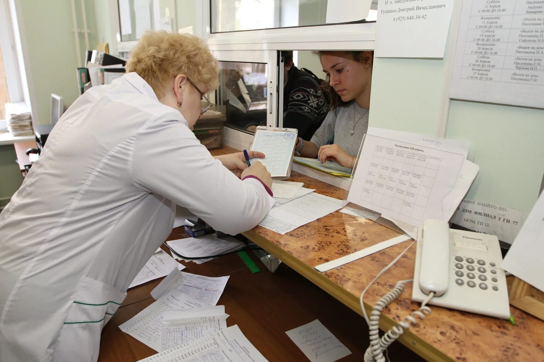 Регистратура поликлиники. Женщина в регистратуре. Регистратура в поликлинике женщина. Картохранилище в поликлинике.