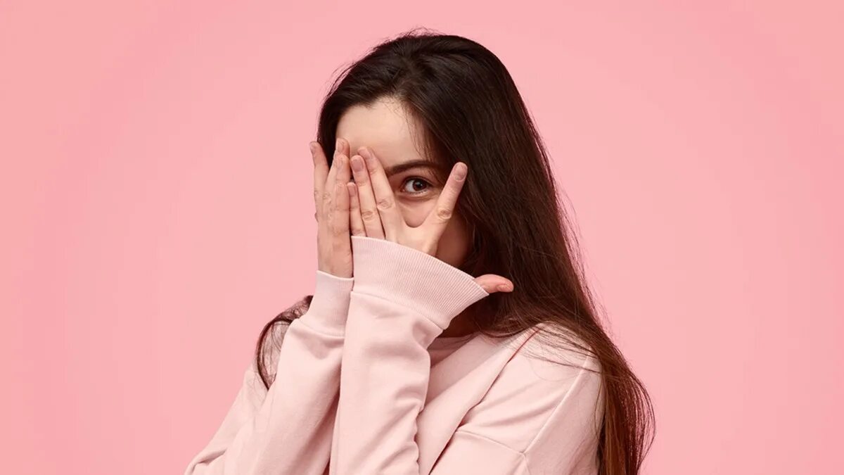 Девушка стесняется камеры. Девушка стесняется камеры. Девушка стесняется. Прячет лицо. Девушка в замешательстве.