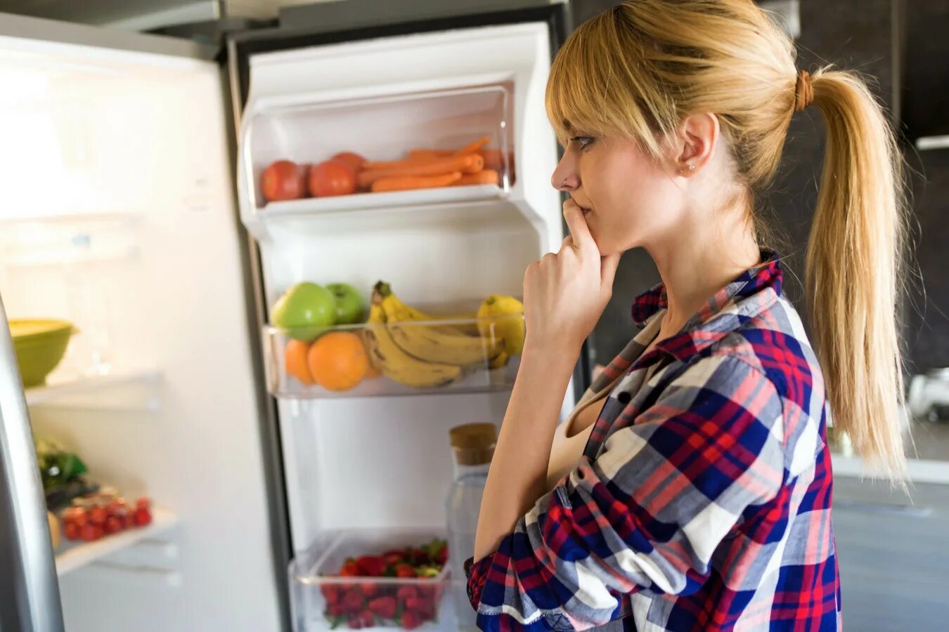 Девушка у открытого холодильника. Холодильник с едой. Заглядывает в холодильник. Хозяйка и холодильник. Есть фрукты на голодный желудок
