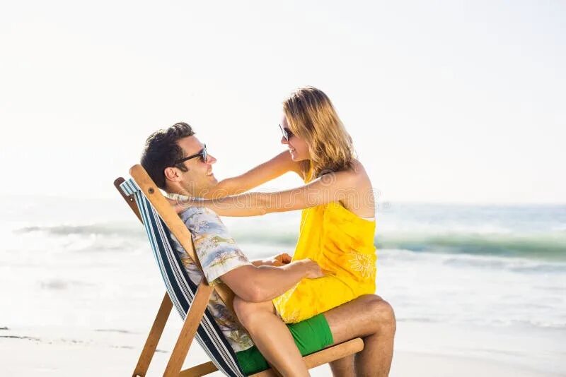 Парень и девушка сидят на пляже. Мужчина сидит на пляже. Женщина сидит на мужчине на пляже. Женщина сидит на коленках на пляже.
