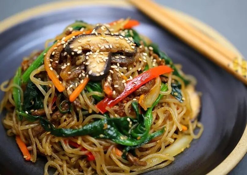 Фунчоза с шампиньонами. Japchae чапчхе. Блюда с лапшой корейская кухня. Лапша рисовая в корейских блюдах.