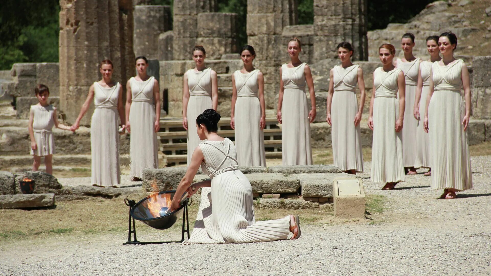 Греческое било. Церемония зажжения олимпийского огня в Греции. Зажжение олимпийского огня в Олимпии. Церемония зажжения олимпийского огня в Греции древние греки. Церемрниязажжения олимпийского огня в Греции.