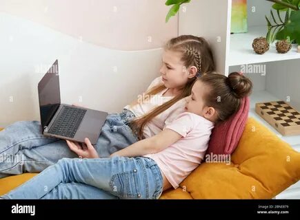 Brother and sister (2-3) with newborn boy (0-1 months) on bed Stock Photo. 