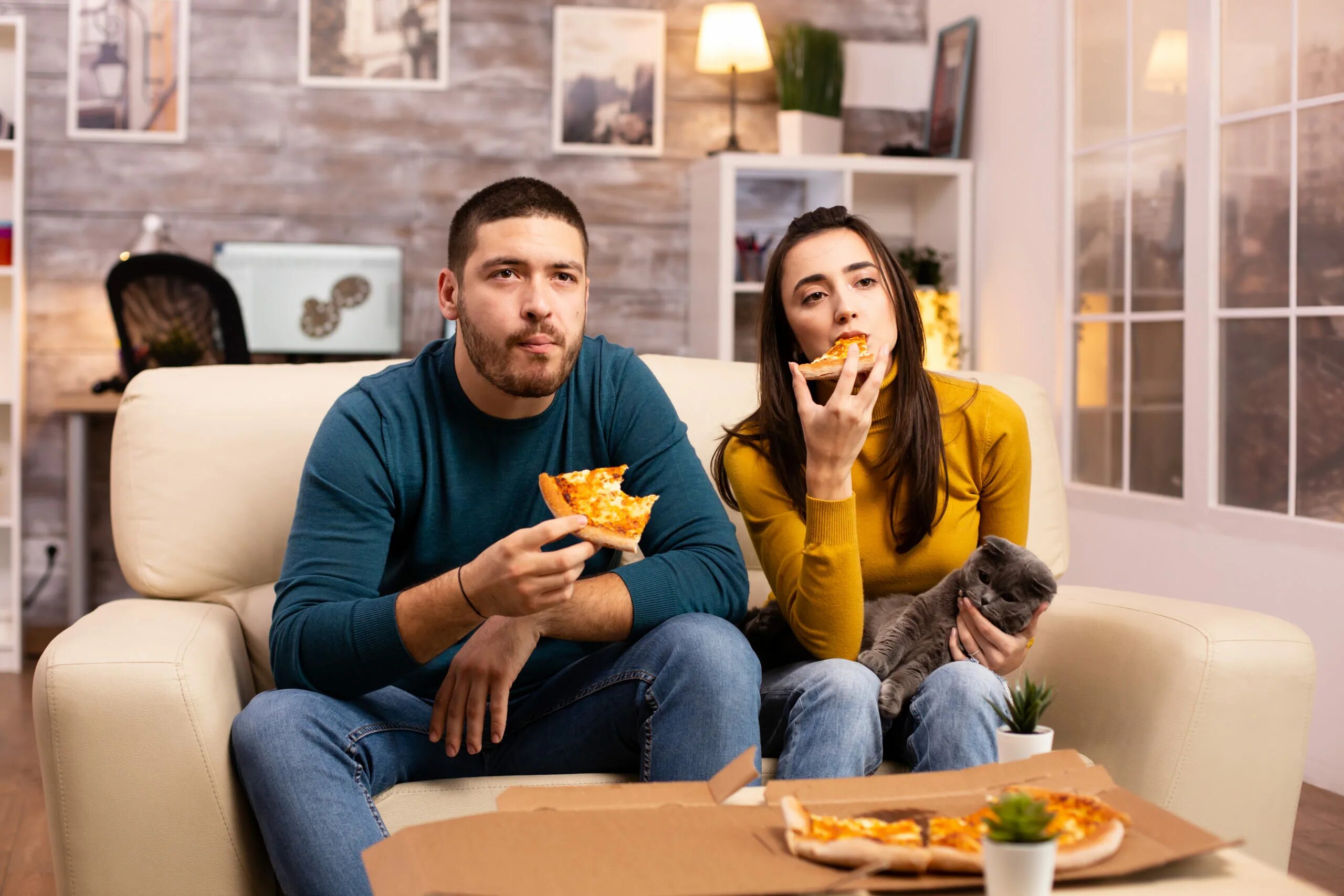 Watch TV while eating. Girls sitting on Sofa watching TV isolated. A man eating while watching TV.