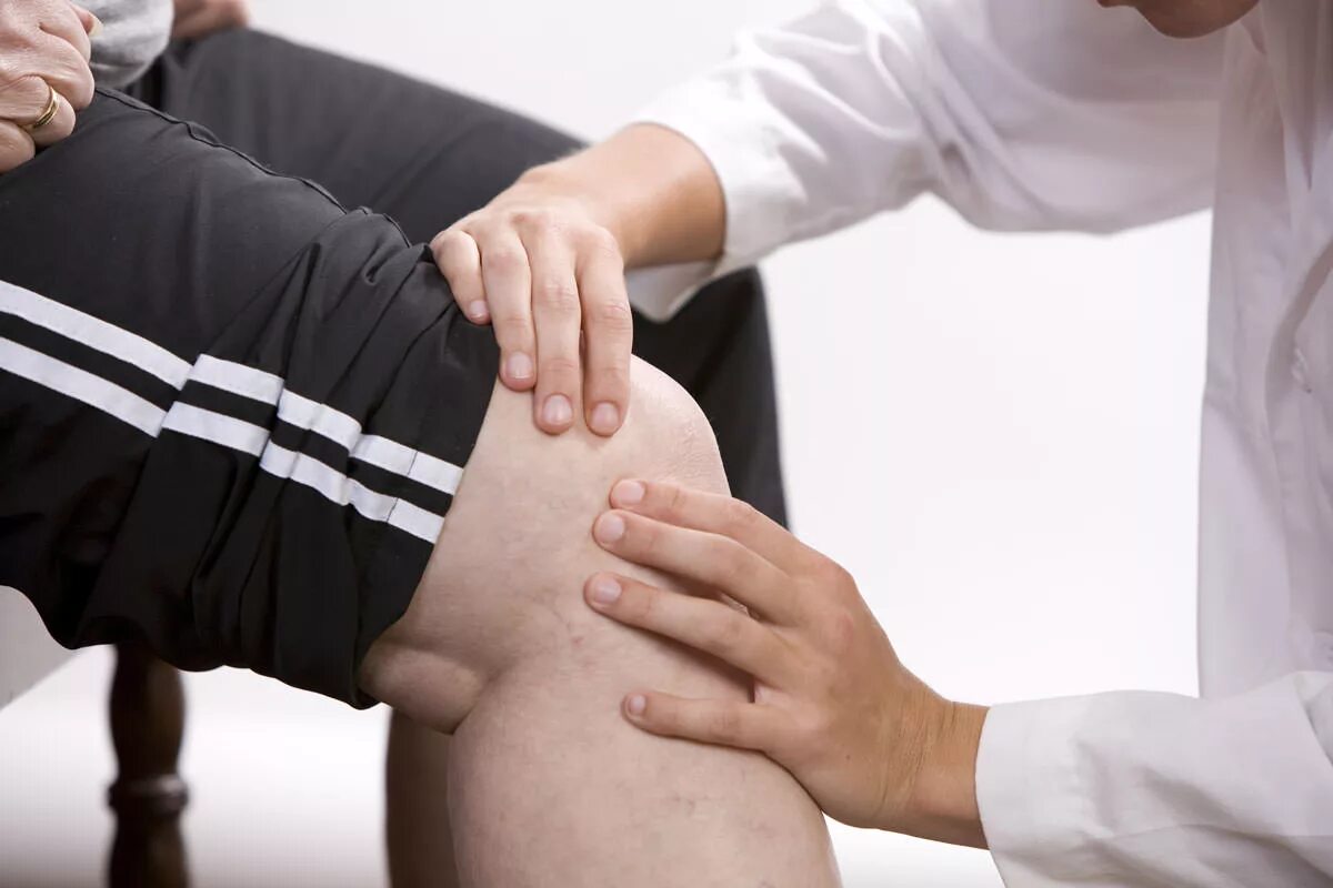 К какому врачу обращаться при болях. Врач осматривает колено. Тугоподвижность суставов. Больное колено. Осмотр сустава колена.