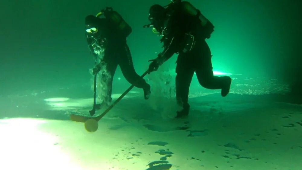 Подледный хоккей. Подледный хоккей шайба перемещается по нижней стороне слоя льда. Подводный хоккей под льодом. Подводный хоккей под льодом. Подледный хоккей.