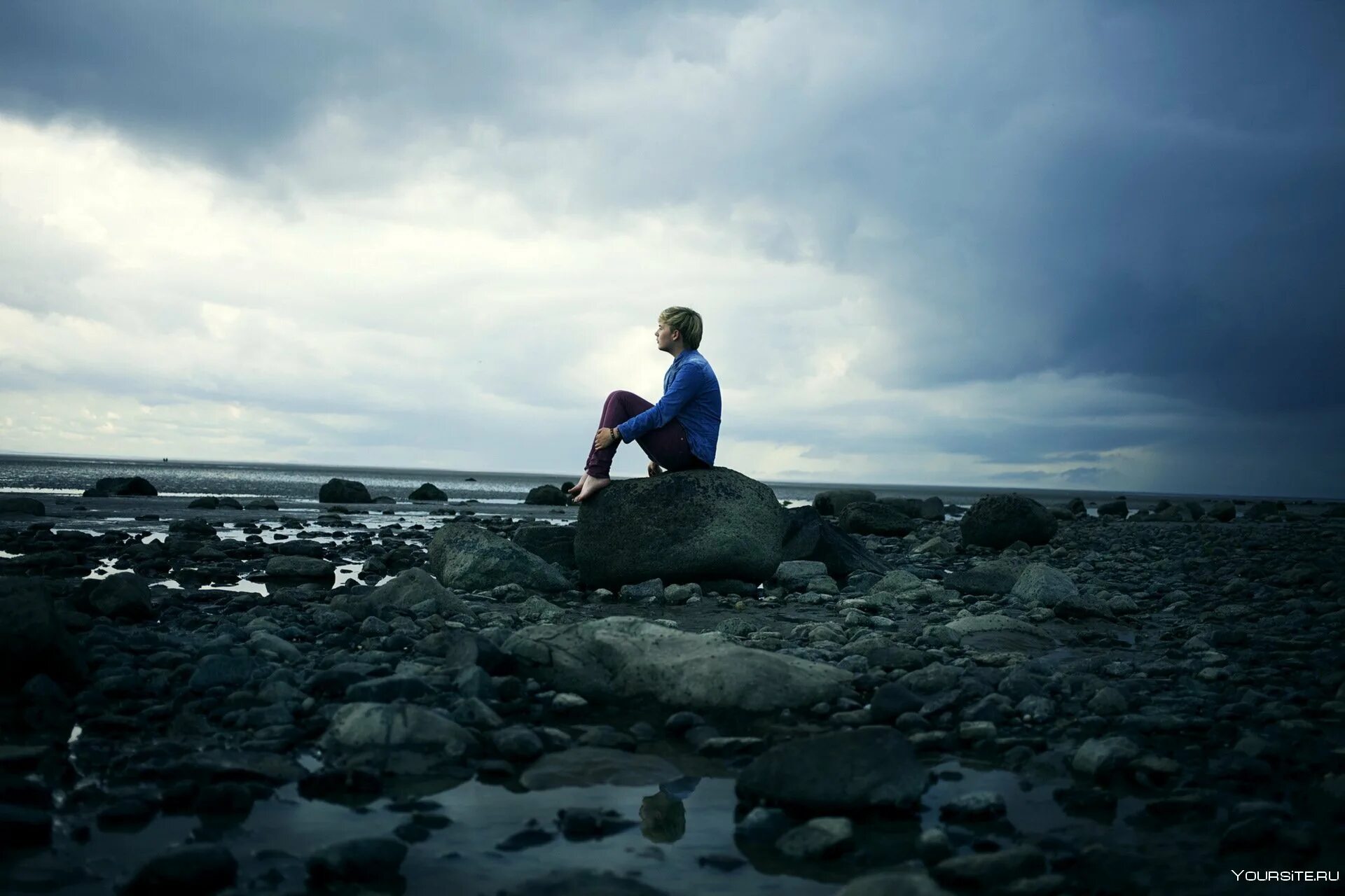 Там в далеком далеке. Одинокий парень. Человек камень. Одинокое море. Человек сидит на берегу.