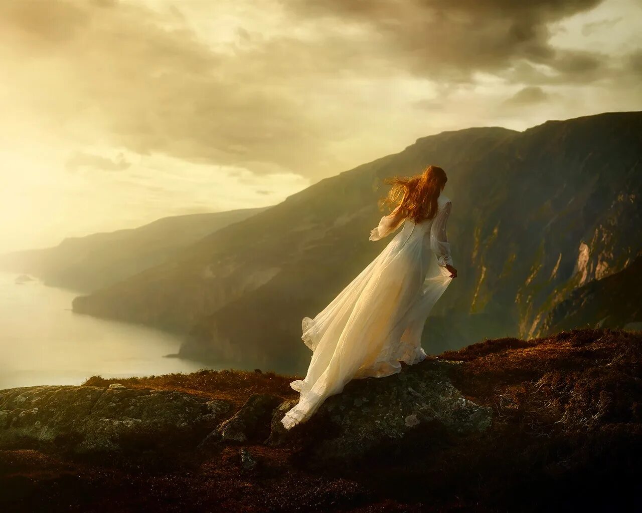 Девушка на обрыве. Девушка на скале. Рыжая девушка в горах. Девушка в длинном платье. Видеть себя в длинном платье