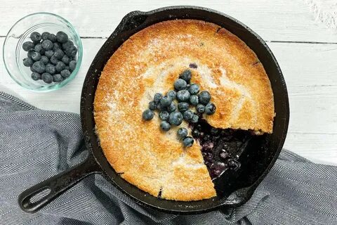 Blueberry Cobbler in a cast iron skillet with slice missing.