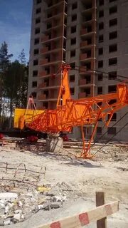 Башенный кран поднимает бетонную плиту массой