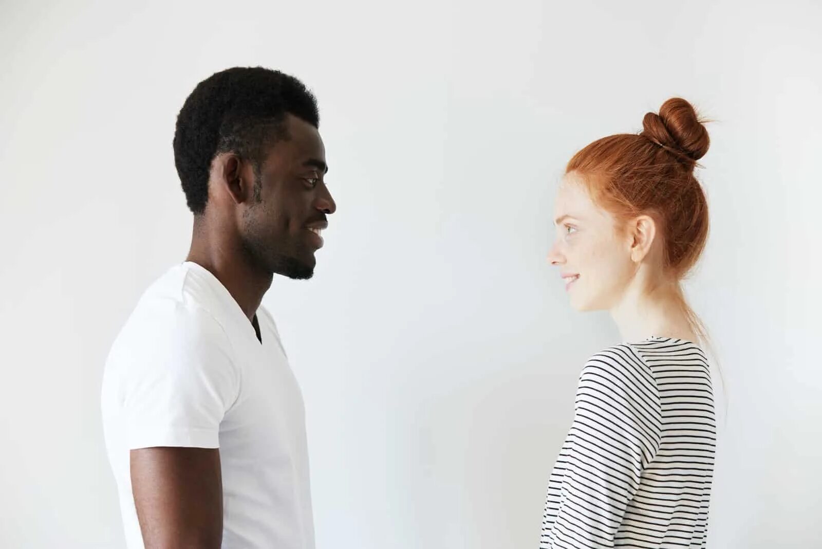 Looking at each other. Рыжий негр. Афроамериканец и белая девушка. Рыжая и темнокожий пара. Темнокожий парень и рыжая девушка.