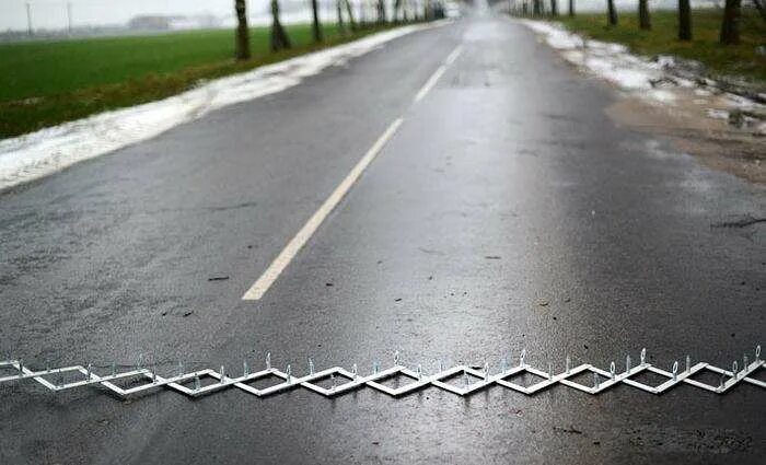 Лента для перекрытия дороги с шипами. Железные шипы. Металлические шипы на дорогах. Дорожный блокиратор дикобраз. Полицейские шипы.